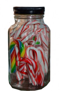 Decorating a fireplace mantel for Christmas with glass jar filled with candy canes.