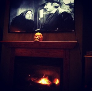 A single, spot-lighted skull, and a scene from a black and white horror movie create a simple but dramatic Halloween mantel